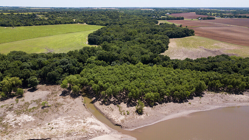 Aerial view of a wooded landscape and open farmland extending toward the horizon
