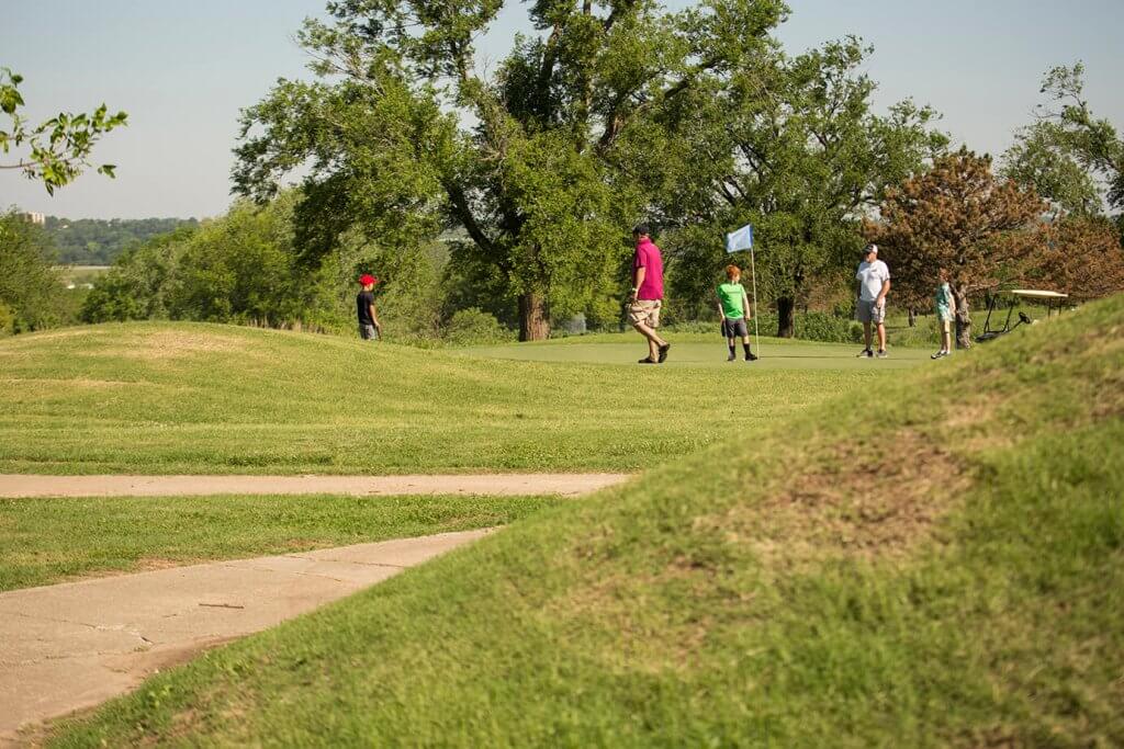 Visitors walk across grassy mounds and paths at a historic earthworks site.