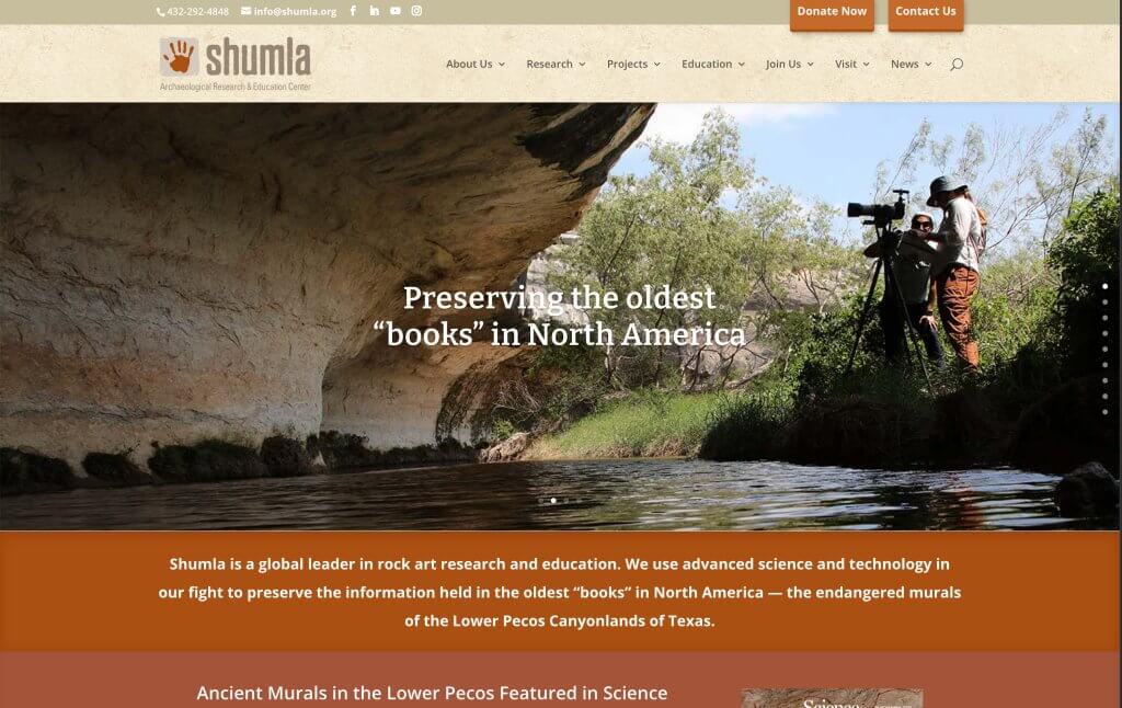 Shumla website banner showing researchers filming rock art along a river beneath a cliff overhang.
