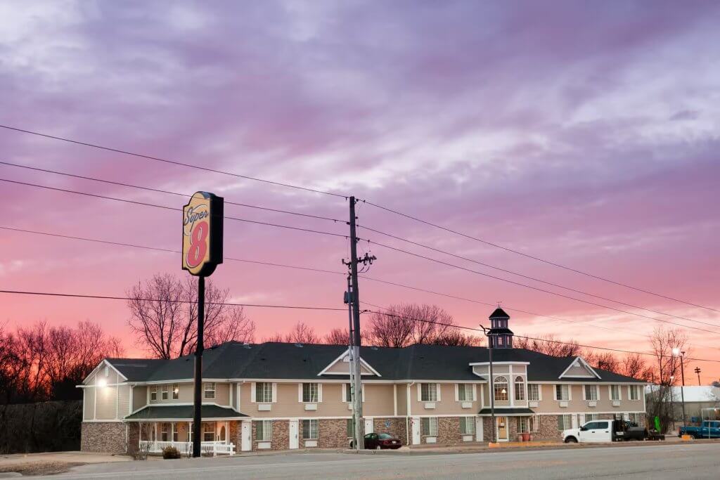 Exterior view of a Super 8 motel at sunset with the roadside sign visible.